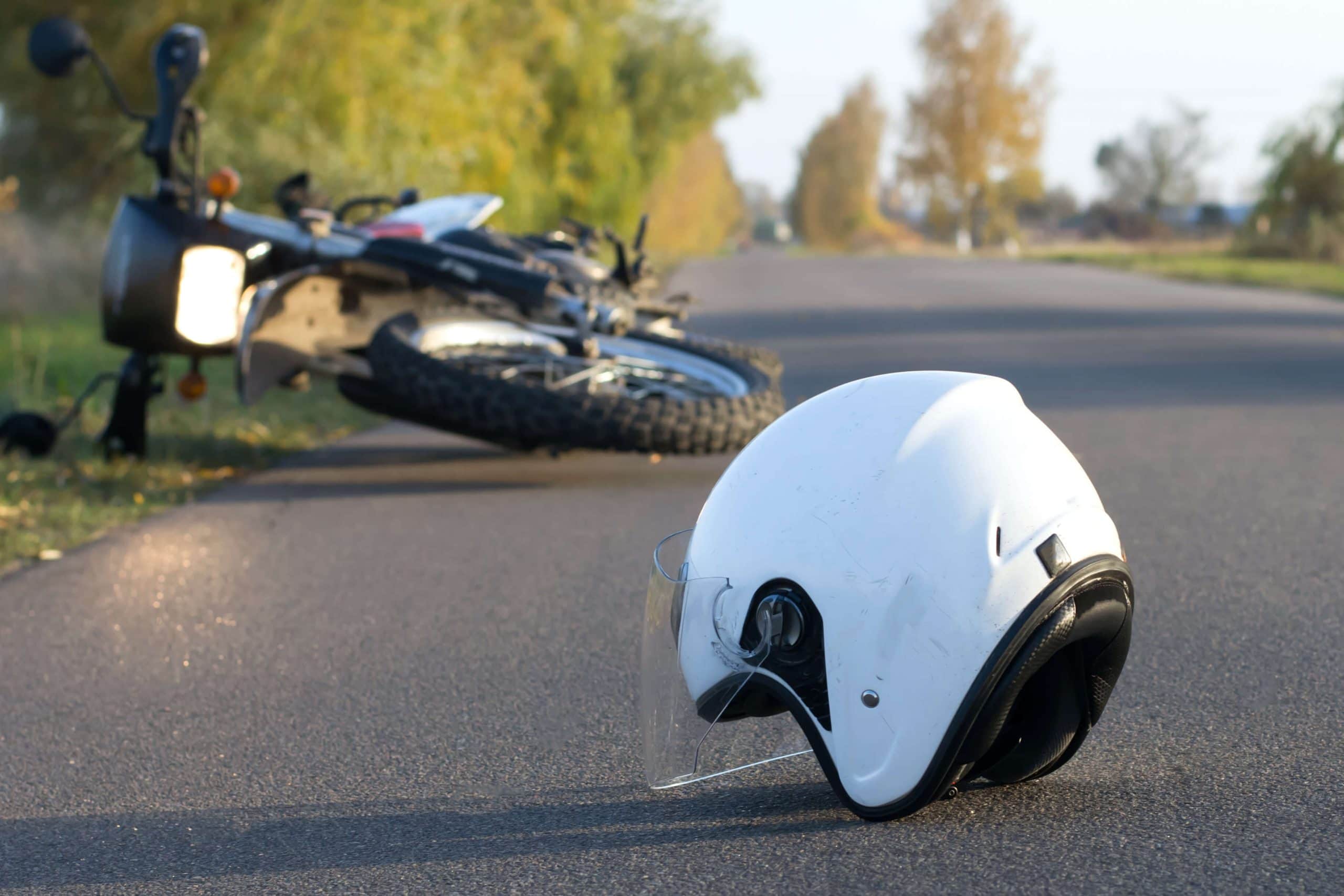 motorcycle helmet on asphalt in front of overturned motorcycle